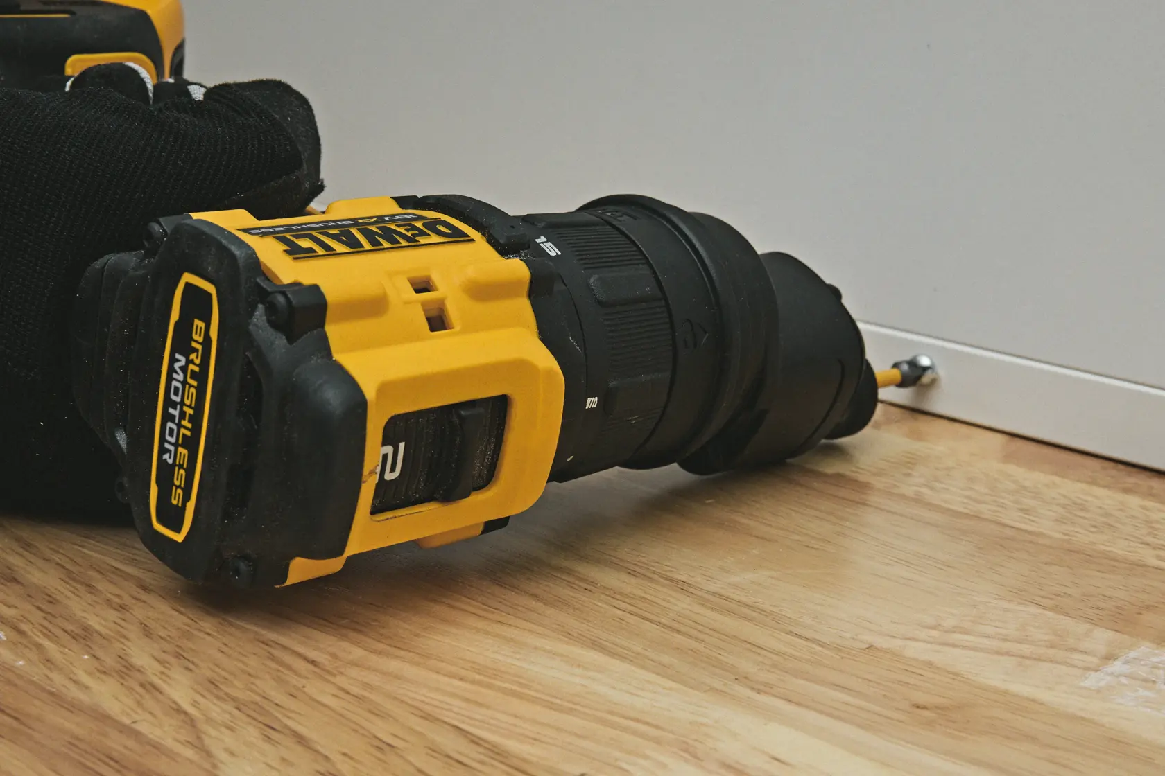 DEWALT drill DCD803P2T-QW, DCD803P2T in use on wood floor, screw to cabinet. Photography product category.
