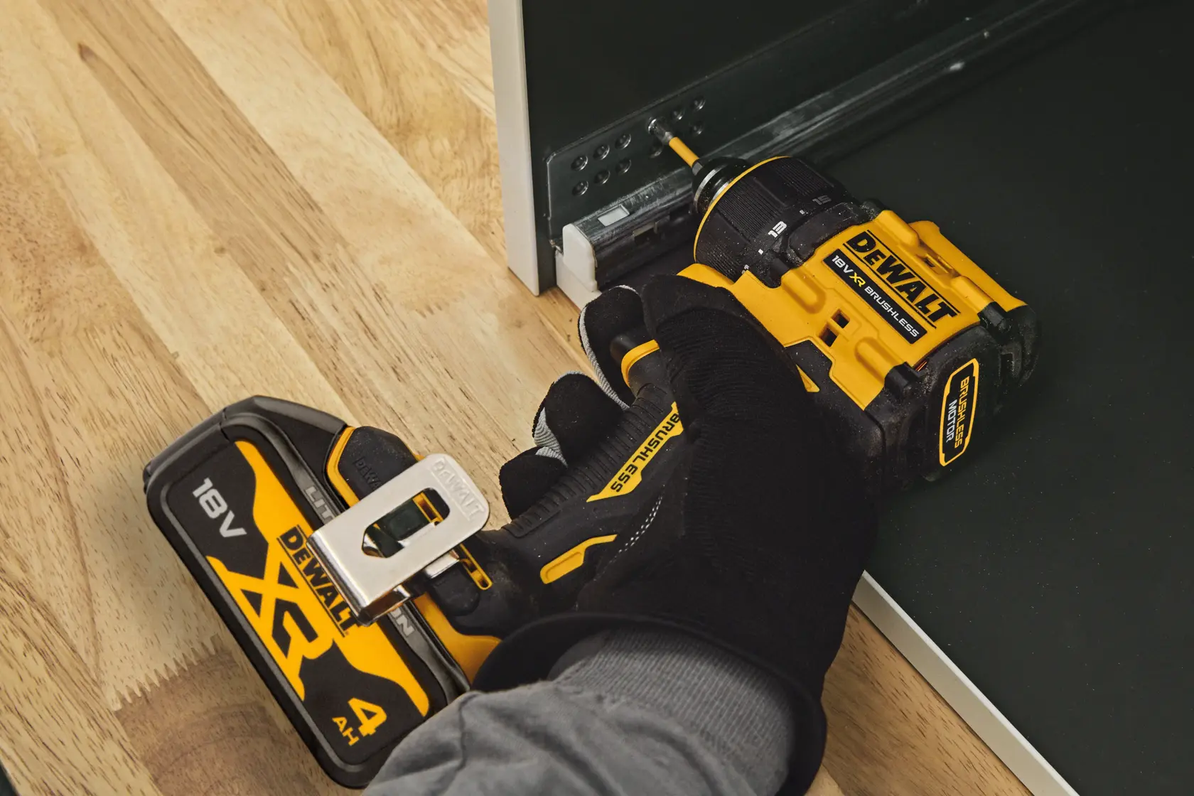A DEWALT DCD803 cordless drill being used to install screws in a metal rail on a wooden surface.