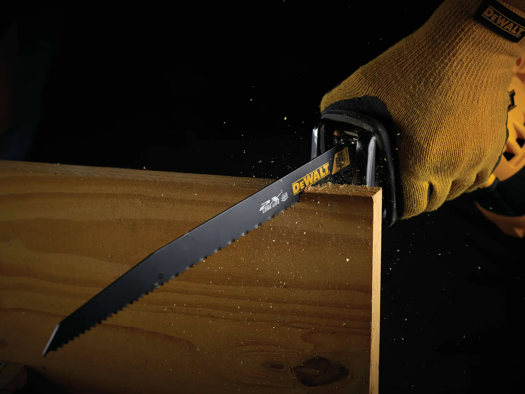 Hoja DEWALT cortando madera, usada por mano con guante. Se ve aserrín.