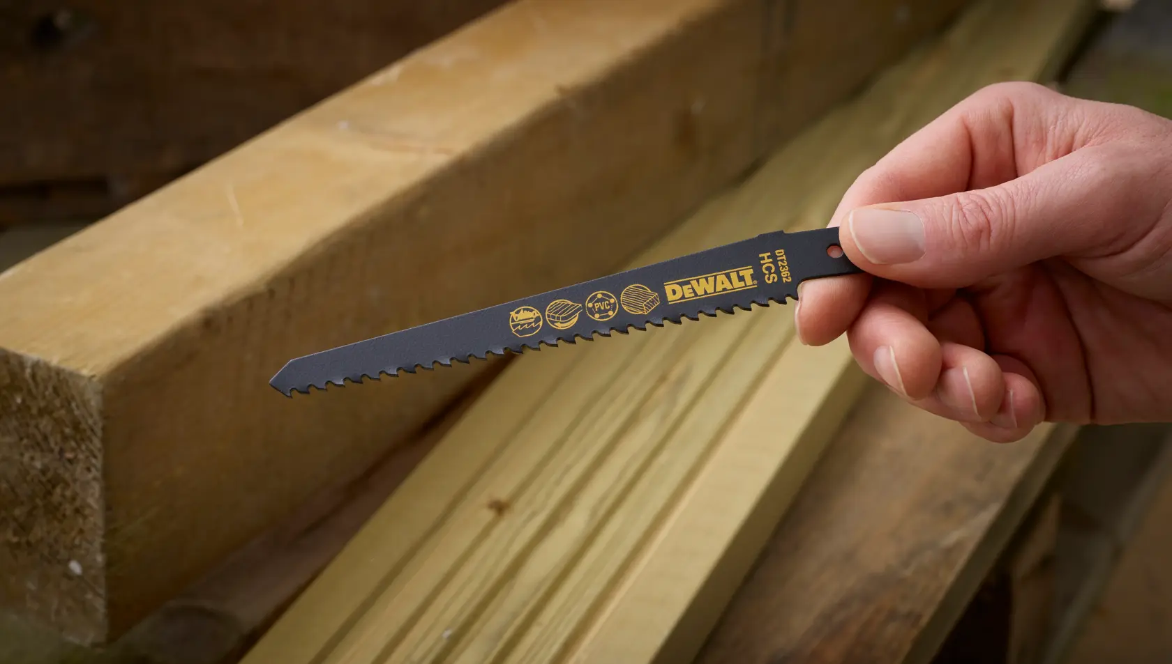 Hand hält DEWALT DT2362 Sägeblatt neben Holzlatten in Werkstatt.