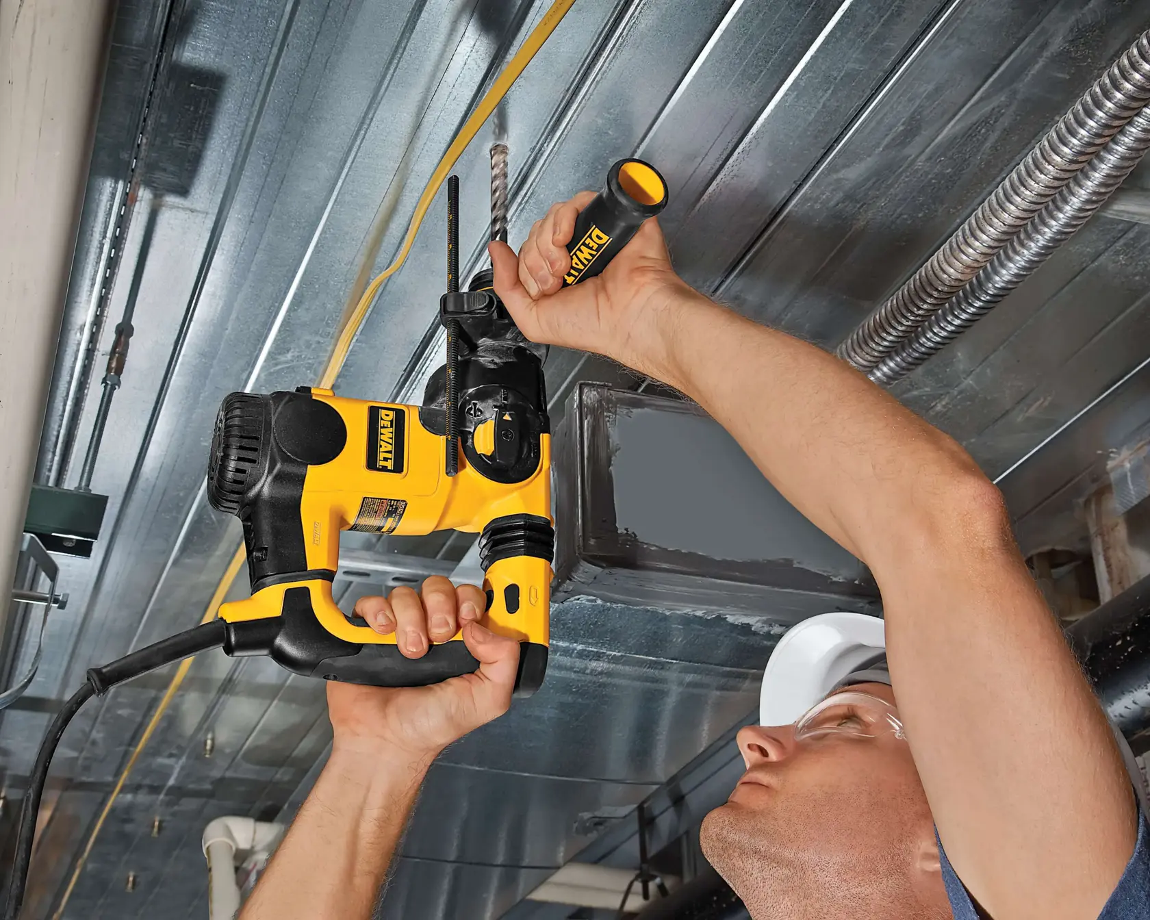 Una persona usa un taladro DEWALT en un techo metálico, sujetando y perforando hacia arriba.